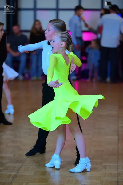 Dancesport competitor: Female dancer: bright yellow long-sleeved latin dress with a flared skirt and wh