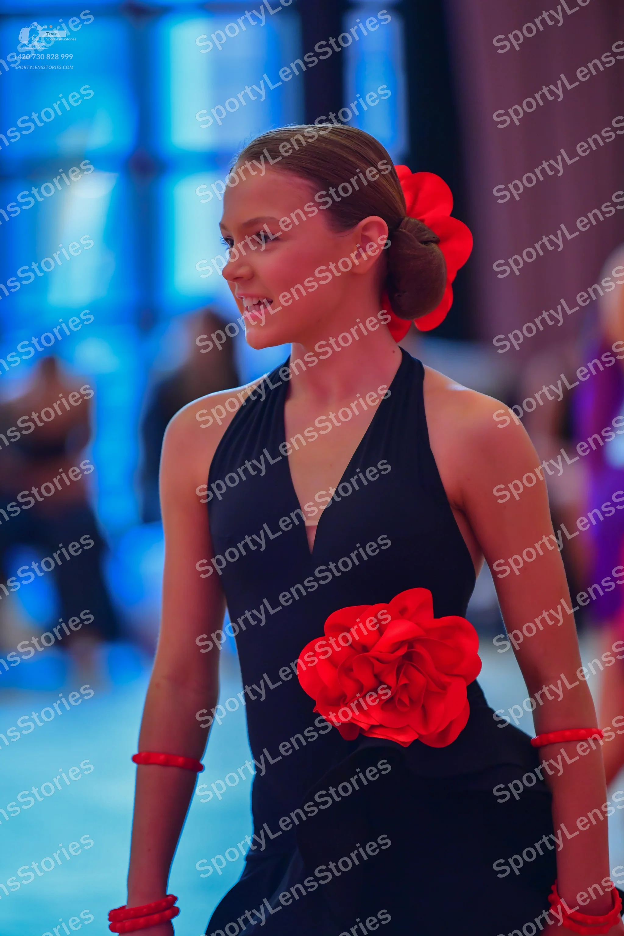 Dancesport competitor: Female dancer: black halter-neck latin dress with a large red fabric flower at t