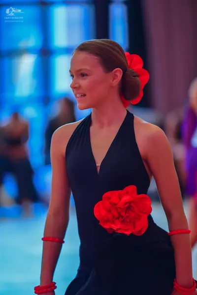 Dancesport competitor: Female dancer: black halter-neck latin dress with a large red fabric flower at t