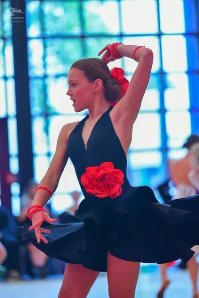 Dancesport competitor: Female dancer: black latin dress with a large red rose on the bodice, a halter n