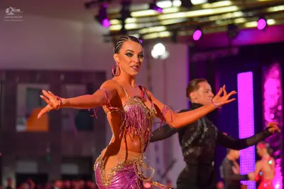 Dancesport competitor: Female dancer: pink and gold sequined Latin dress with fringe and nude-colored m