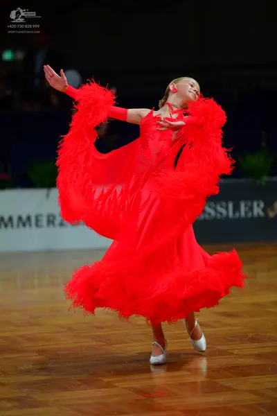 Dancesport competitor: Female dancer: red Latin dance dress with voluminous red feather or fringe embel