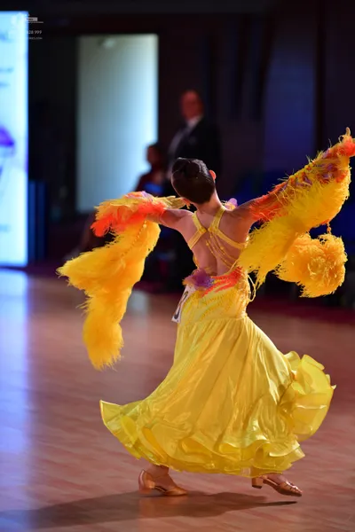 Dancesport competitor: Female dancer: bright yellow ballroom dress with a voluminous, multi-layered ruf