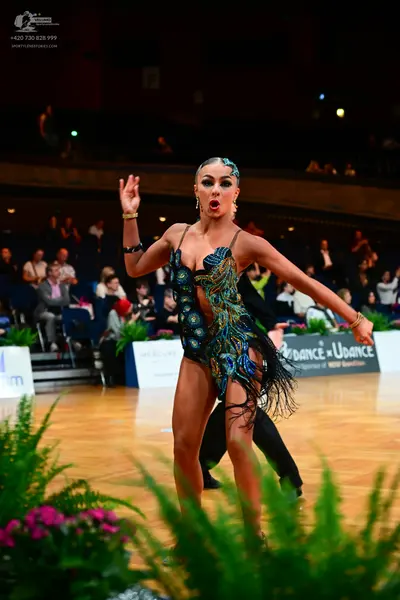 Dancesport competitor: Female dancer: dark/black latin bodysuit with colorful peacock-style sequin and 