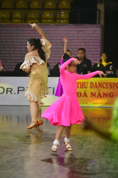 Dancesport competitor: Female dancer 1: gold Latin dance dress with large ruffled sleeves and a flared 