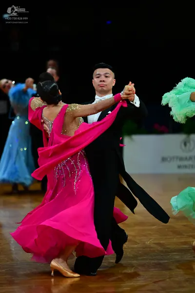 Dancesport competitor: Central female dancer: bright pink ballroom gown with a sequined bodice