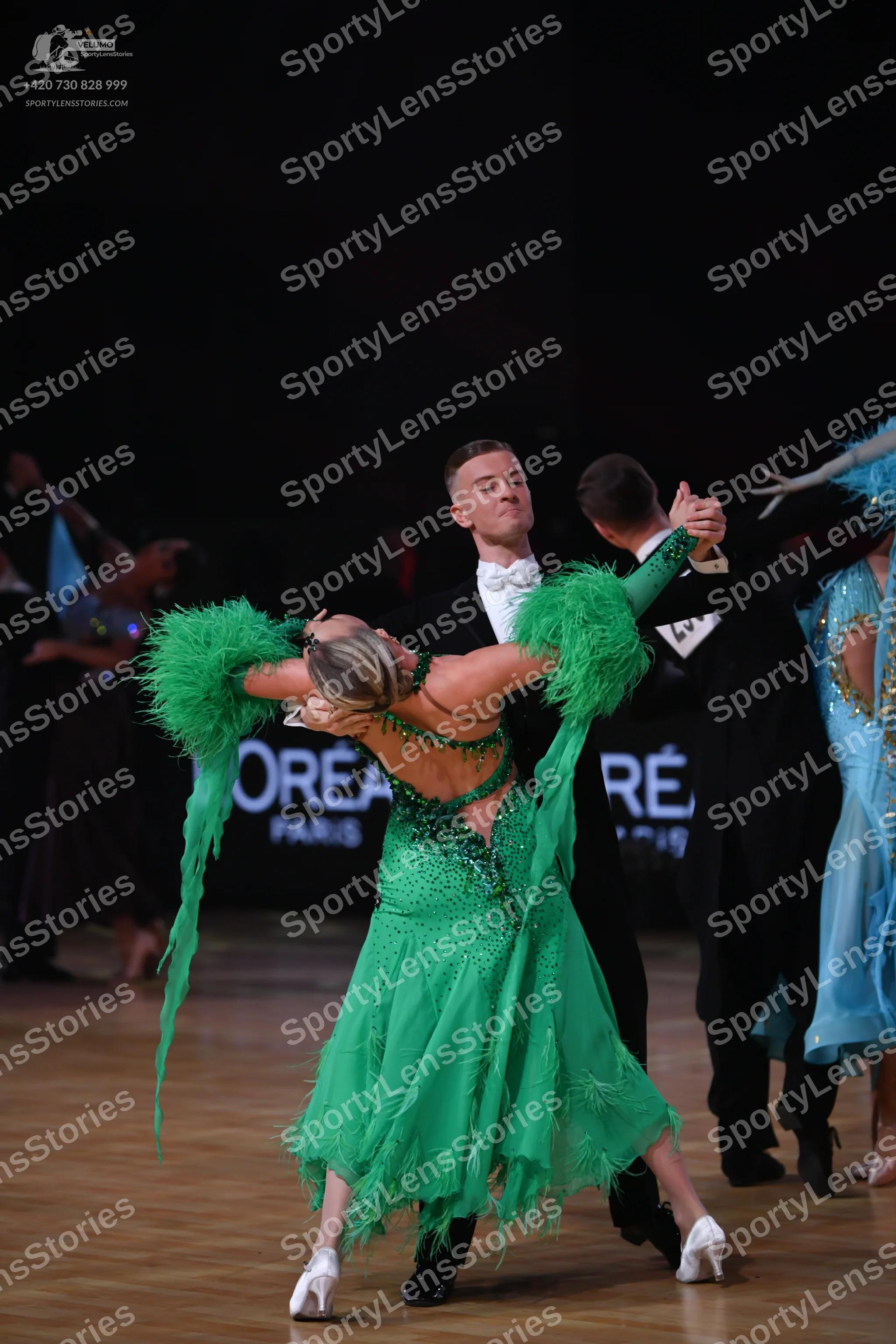 Dancesport competitor: Central female dancer: bright green Latin dress with long fringe on the sleeves