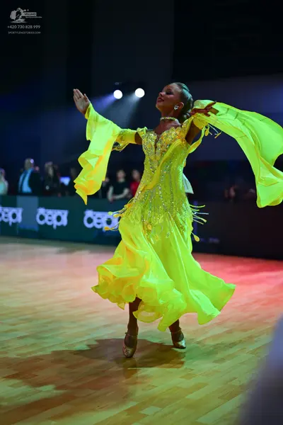 Dancesport competitor: Female dancer: lime green Latin dance dress with sequins, featuring large flowin