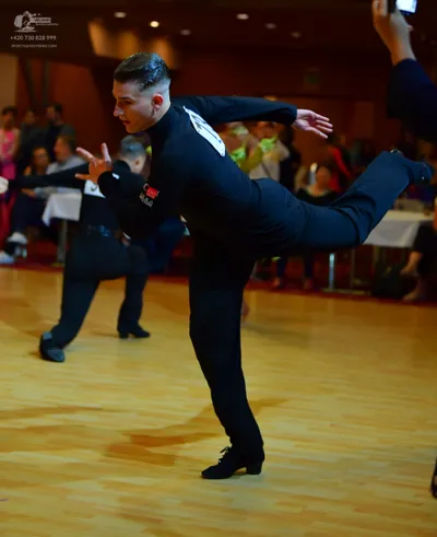 Dancesport competitor: Male dancer in foreground: black long-sleeved shirt and black trousers