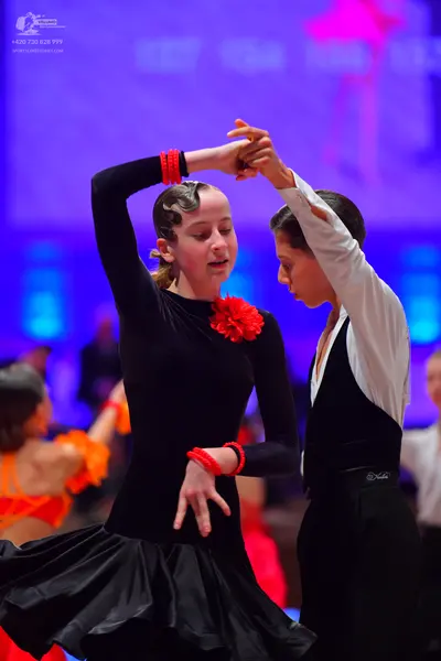 Dancesport competitor: Female dancer: black long-sleeved Latin dress with a red flower embellishment on