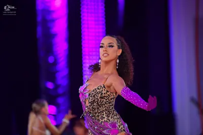 Dancesport competitor: Female dancer in foreground: leopard print Latin dress with purple sequin embell