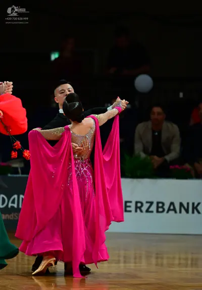 Dancesport competitor: Female dancer: bright pink ballroom gown with a sequined bodice, sheer back pane