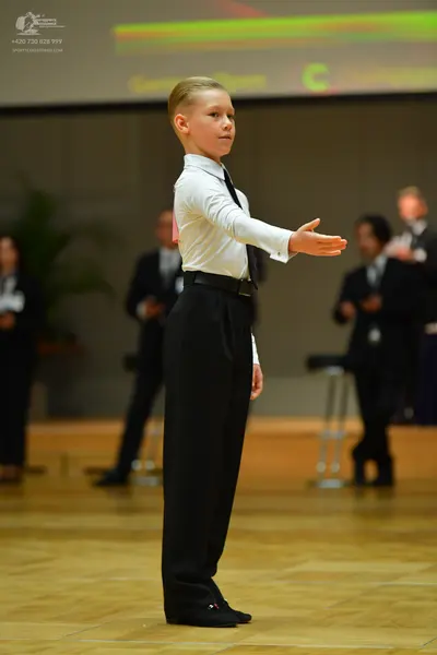 Dancesport competitor: Male dancer: white long-sleeved shirt, black necktie, black trousers, and a blac