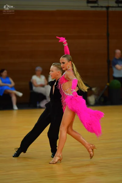 Dancesport competitor: ** Latin dress
*   **Color:** Bright pink
*   **Fabric:** Likely satin or a simi