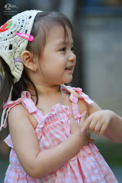 Dancesport competitor: The child is wearing a pink and white gingham pattern dress with ruffles