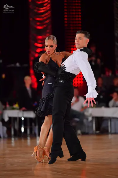 Dancesport competitor: Male dancer: white long-sleeved shirt with ruffled cuffs and black trousers