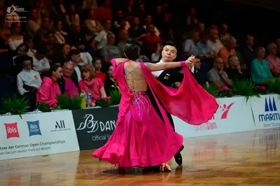 Dancesport competitor: Female dancer: bright pink Latin dance dress with a flowing skirt and backless d