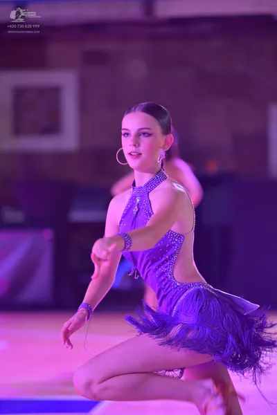Dancesport competitor: Female dancer: purple Latin dance dress with sequins and rhinestones, featuring 