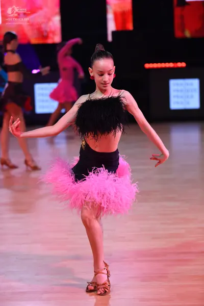 Dancesport competitor: Female dancer (foreground): black latin costume with black feather detail on the