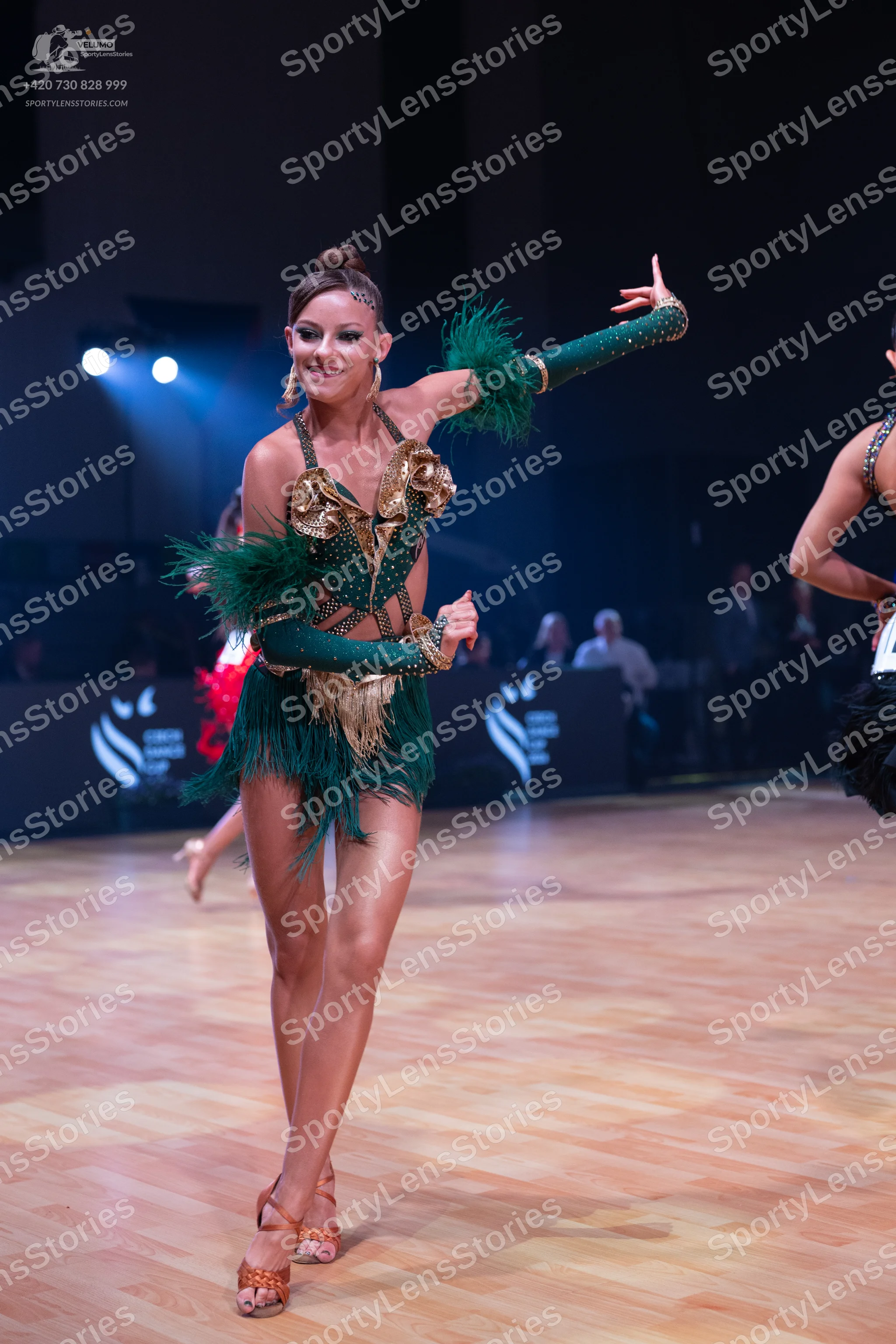 Dancesport competitor: Female dancer: emerald green Latin dress with gold sequin bodice and long green