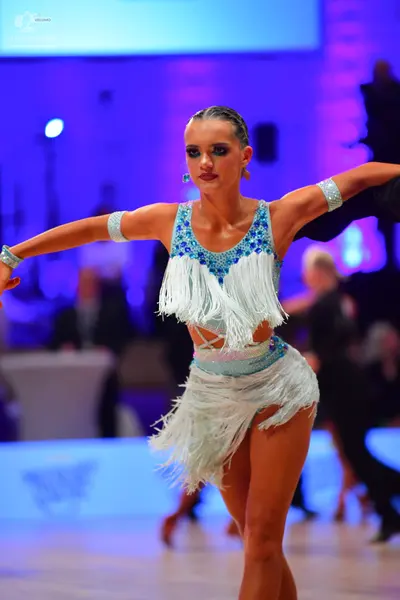 Dancesport competitor: Female dancer: light blue latin costume with sequins and white fringe, and match