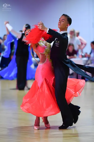 Dancesport competitor: Female dancer: red/coral Latin dress with a sequined bodice, side cutouts, a lar