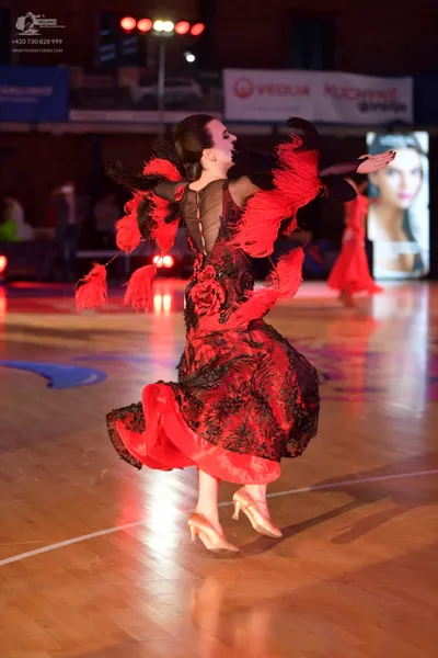 Dancesport competitor: Female dancer: red and black ballroom dress with black lace pattern and large re