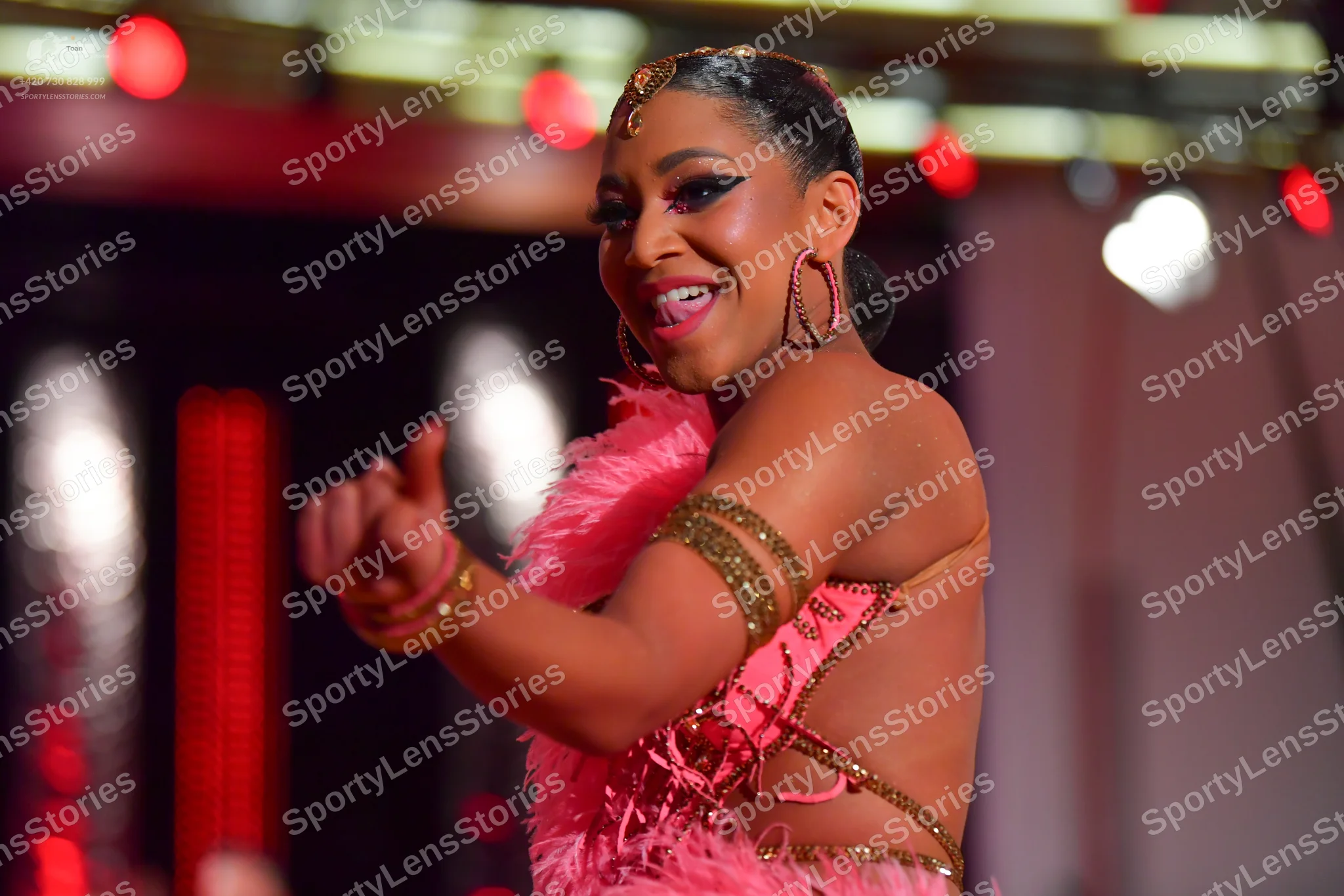 Dancesport competitor: Female dancer: pink latin dress with pink feathers and metallic/gold embellishme