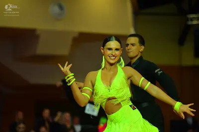 Dancesport competitor: Female dancer: neon yellow latin dress with fringe and side cutouts, and matchin