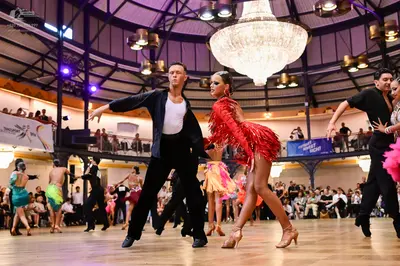 Dancesport competitor: Male dancer in foreground: black shirt and black trousers