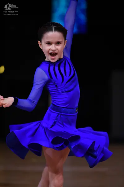 Dancesport competitor: Female dancer: royal blue latin dress with long sleeves, a flared ruffled skirt,
