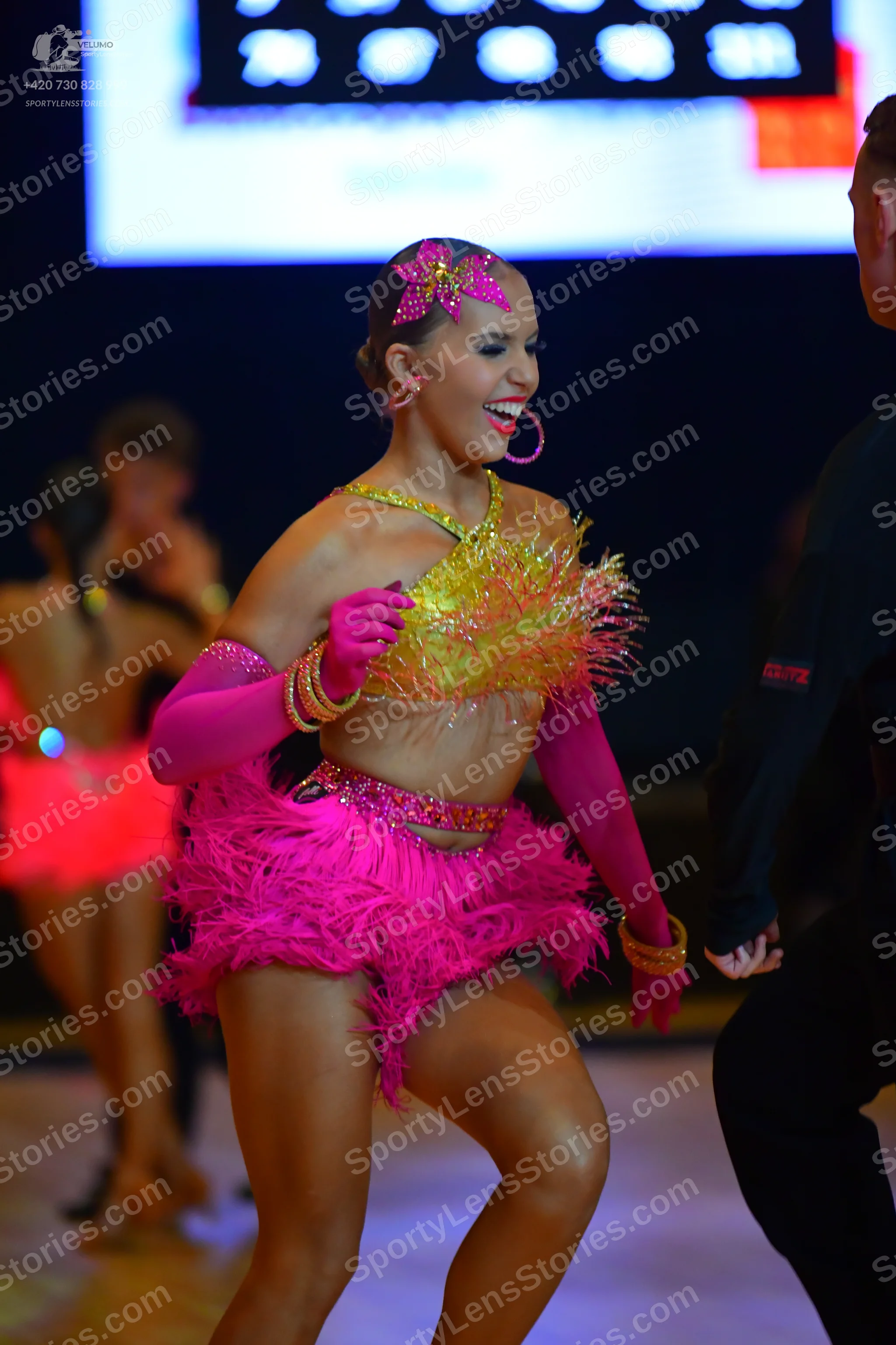 Dancesport competitor: Female dancer: bright pink and yellow/gold Latin dance costume with sequins and 
