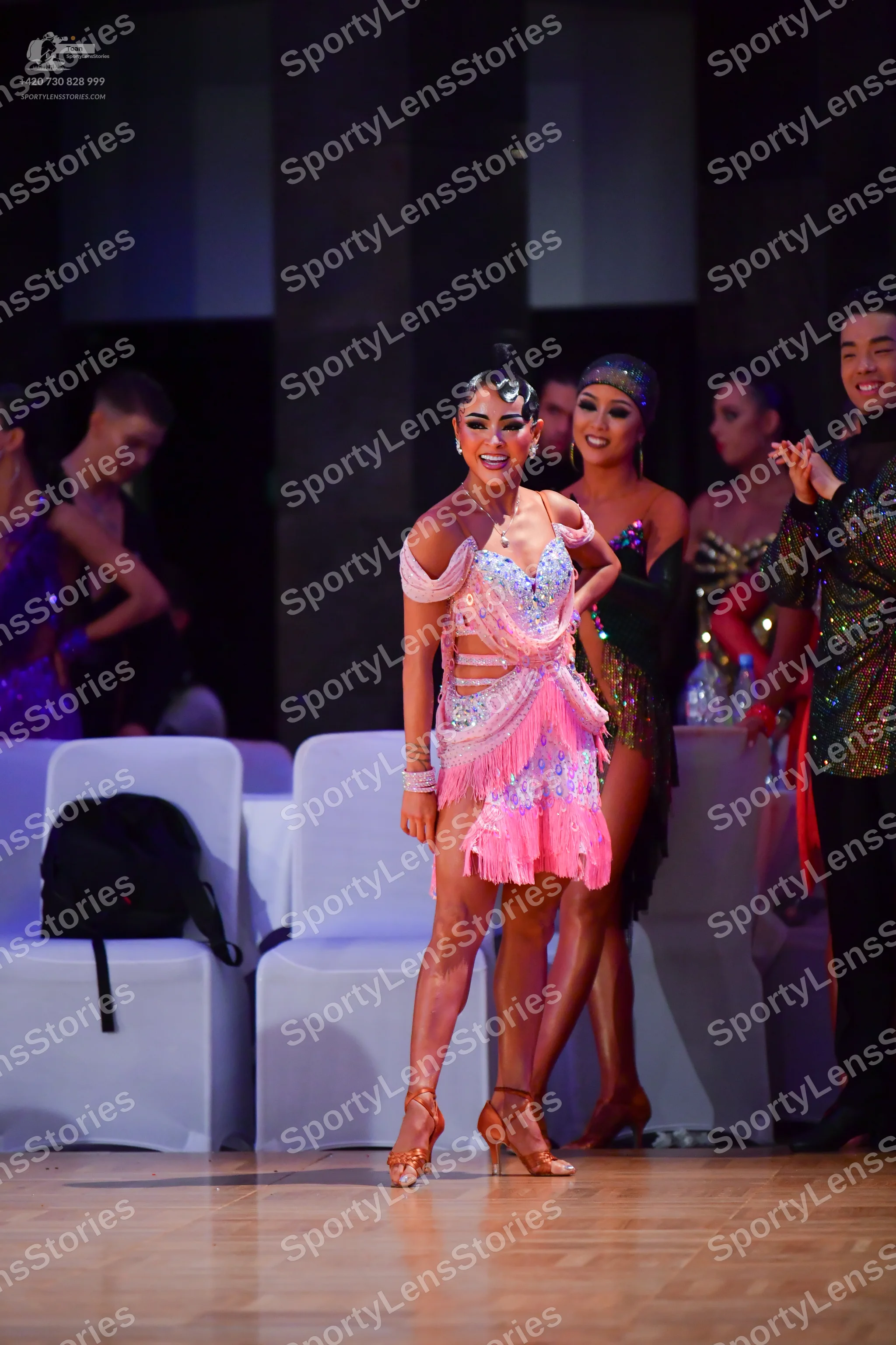 Dancesport competitor: Central female dancer: pink Latin dress with a sequined bodice, off-the-shoulder
