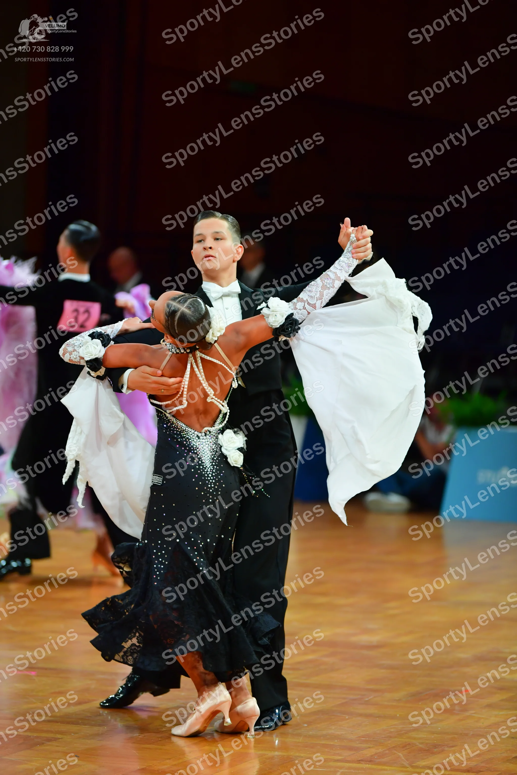 Dancesport competitor: Male dancer in foreground: black suit, white shirt, and white bow tie