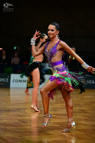 Dancesport competitor: Female dancer 1: purple, green, and pink latin dress with sequins and long fring