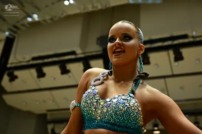 Dancesport competitor: Female dancer: teal/turquoise Latin-style crop top heavily embellished with larg