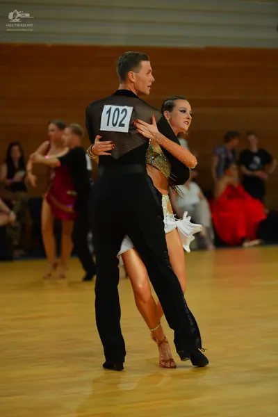 Dancesport competitor: Male dancer (foreground): black long-sleeved shirt and black trousers