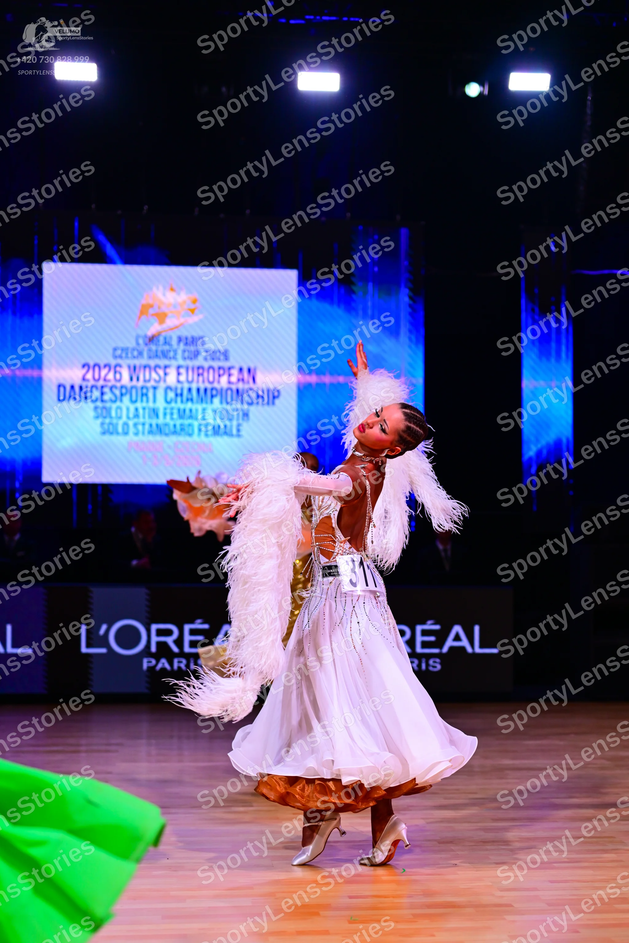 Dancesport competitor: Female dancer: white ballroom gown with large white feather trim on the shoulder
