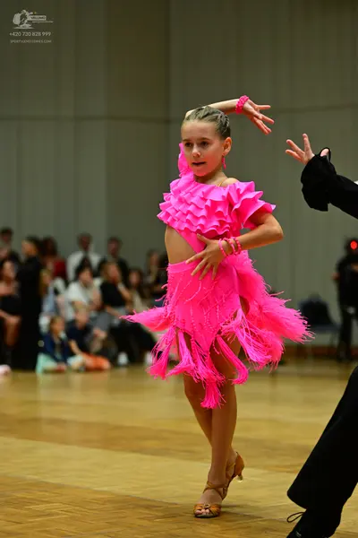 Dancesport competitor: Female dancer: bright pink Latin dance dress with layers of fringe and ruffles, 