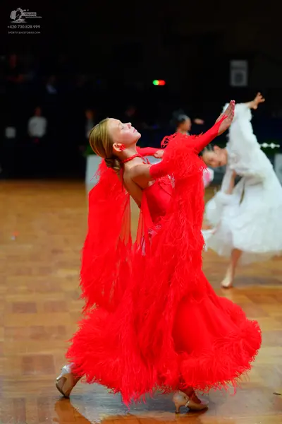 Dancesport competitor: Female dancer 1: red latin dress with long sleeves, heavily decorated with fring