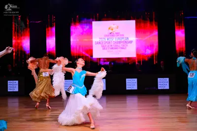 Dancesport competitor: Female dancer on the left: gold Latin dress with a ruffled skirt