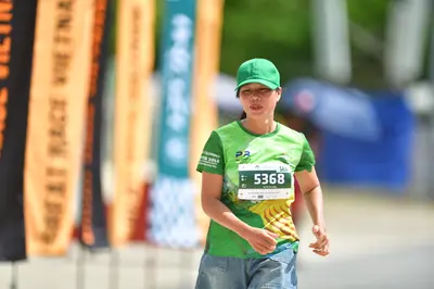 Marathon runner #5368: Runner 1: green jersey with yellow pattern, green cap, light blue denim shorts