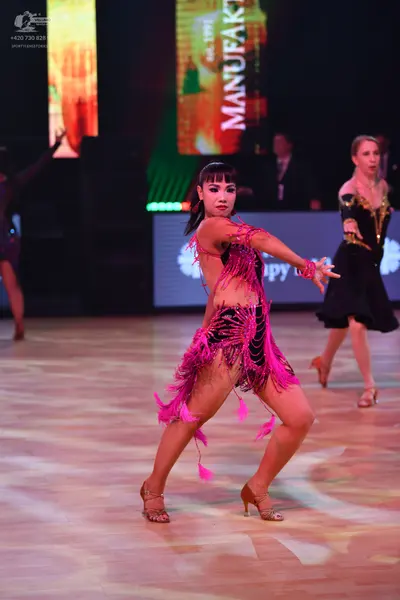 Dancesport competitor: Central female dancer: magenta pink Latin dance costume with long fringe and seq