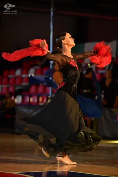Dancesport competitor: Female dancer: black ballroom gown with a red sequined bodice, sheer mesh upper 