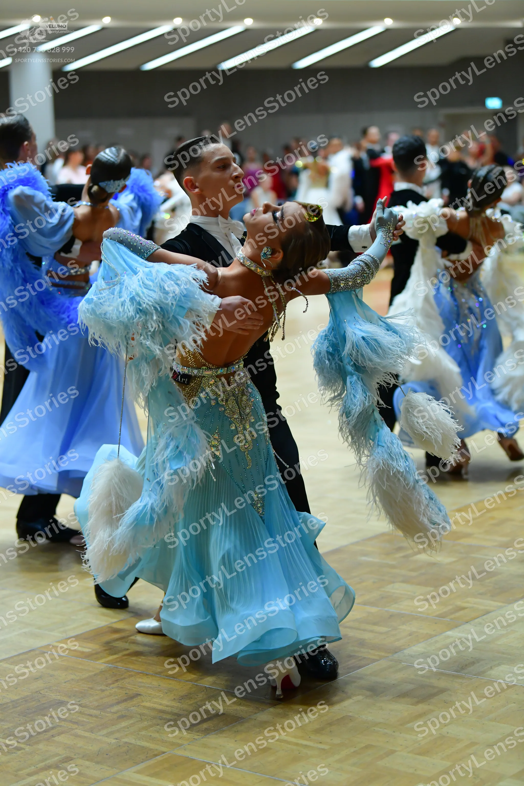 Dancesport competitor: Male dancer in center: black suit, white shirt, and black bow tie