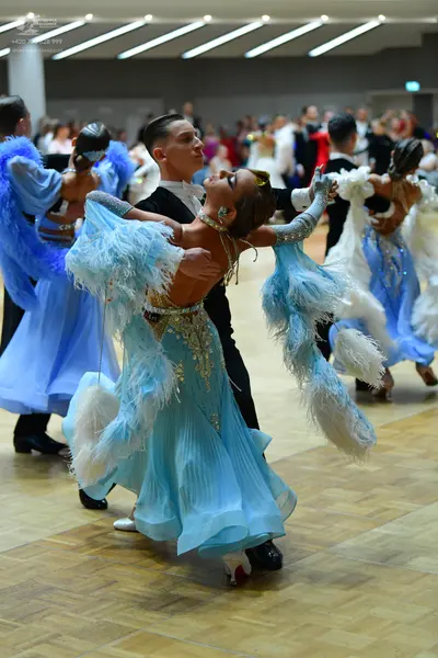 Dancesport competitor: Male dancer in center: black suit, white shirt, and black bow tie