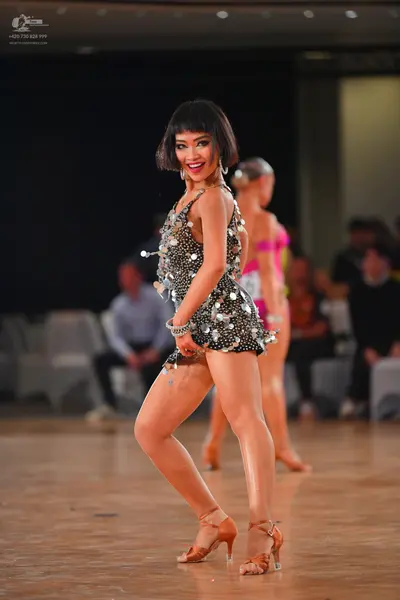 Dancesport competitor: Female dancer: black latin dress with large silver sequins and thin straps, acce