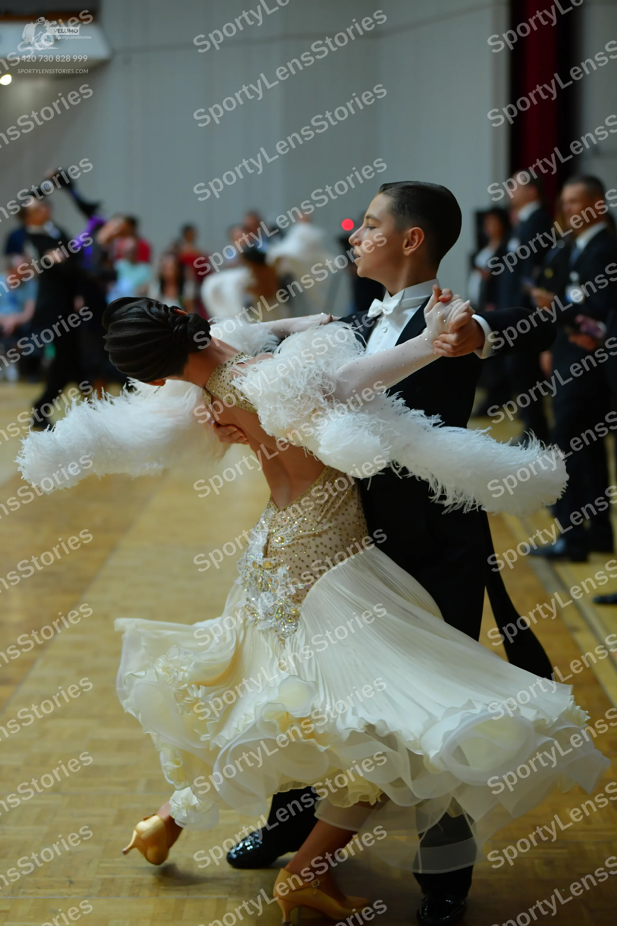 Dancesport competitor: Female dancer: white/cream ballroom gown with a sequined bodice, large fluffy wh