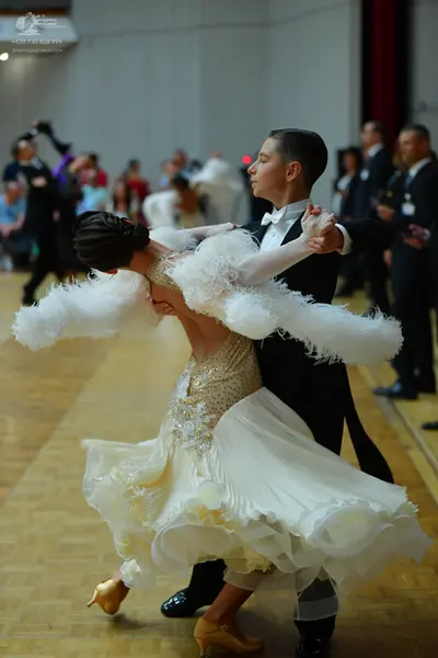 Dancesport competitor: Female dancer: white/cream ballroom gown with a sequined bodice, large fluffy wh
