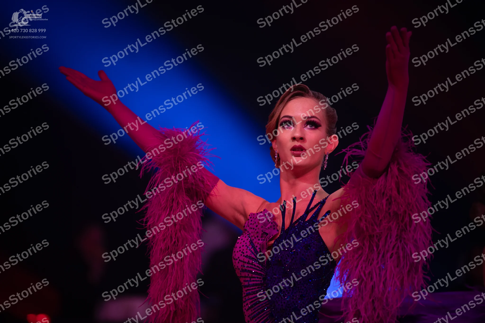 Dancesport competitor: Female dancer: deep purple Latin dress with voluminous feather-like sleeves and